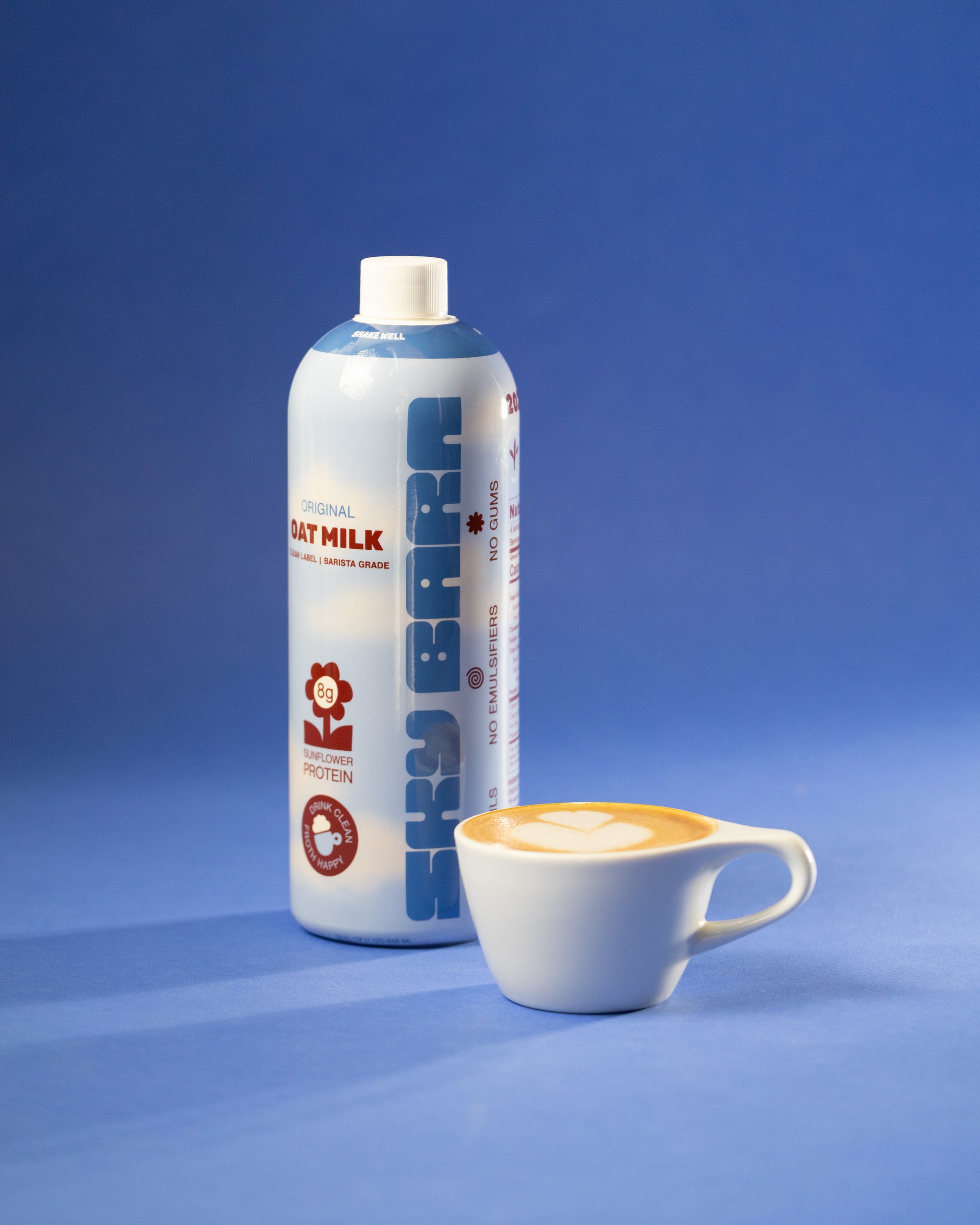 Bottle of Sky Barn milk next to a cup of coffee on a blue background