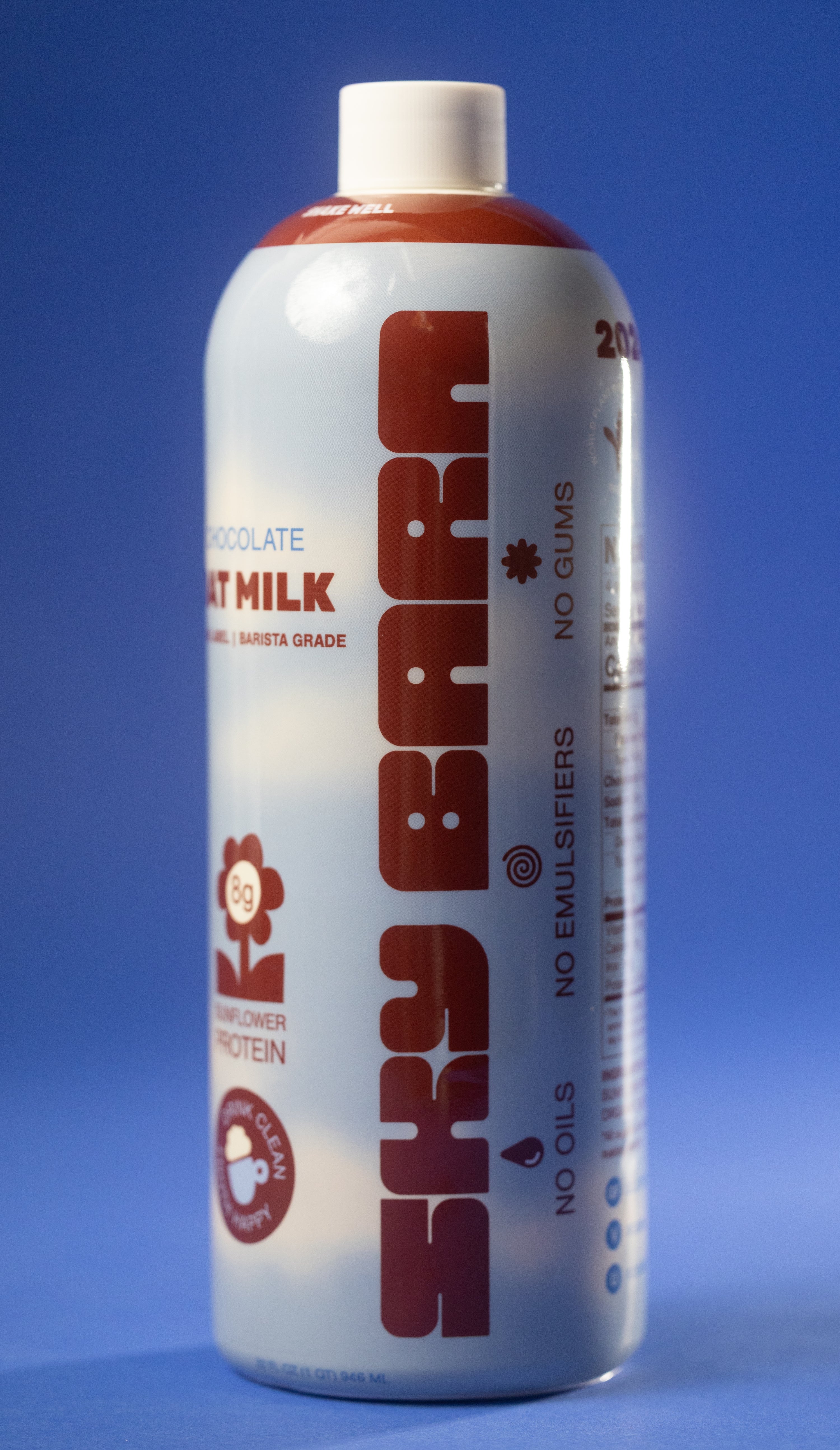 Barista grade bottle of chocolate oat milk with sunflower protein on a cloudy sky background