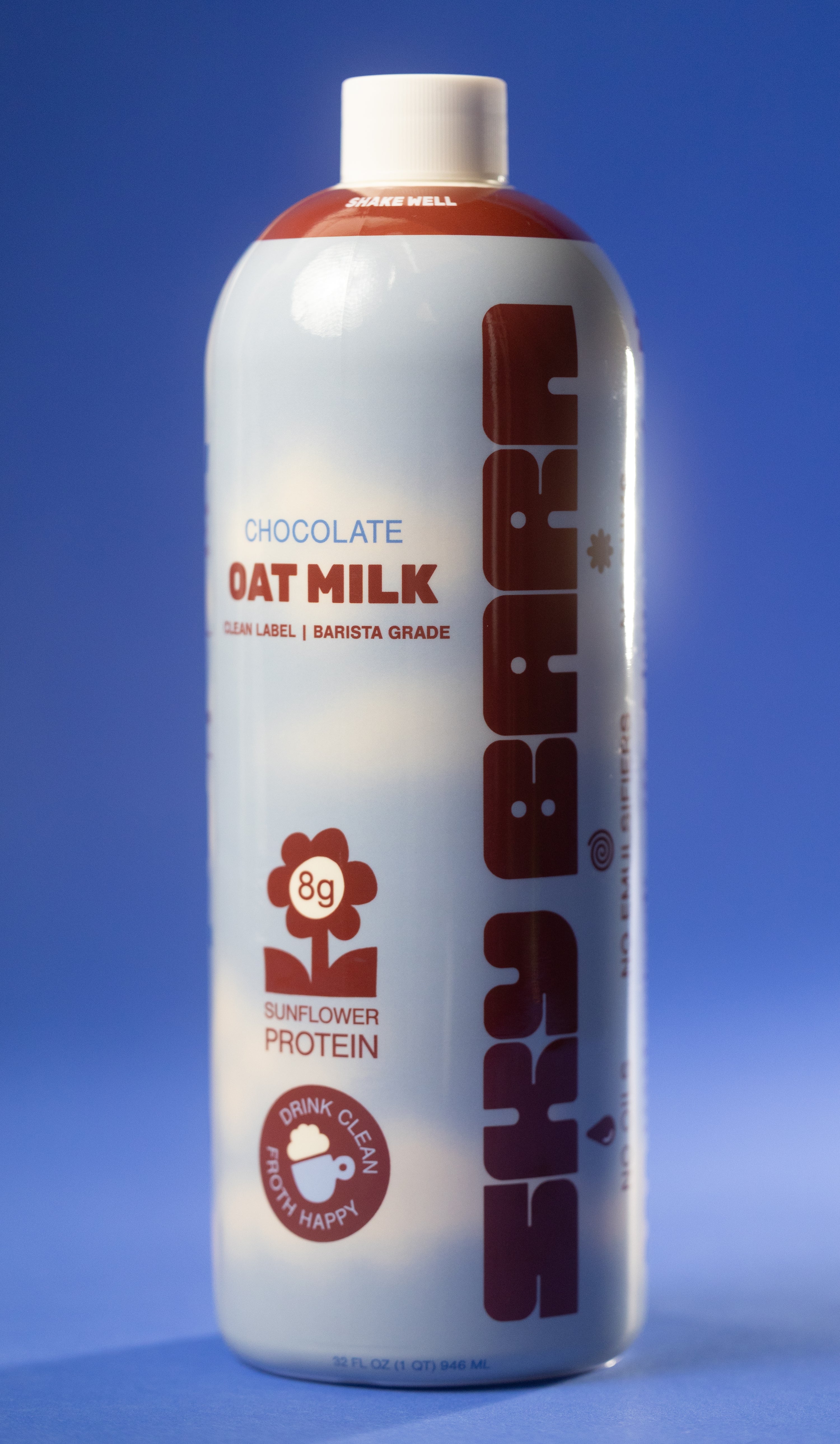 Barista grade bottle of chocolate oat milk with sunflower protein on a cloudy sky background