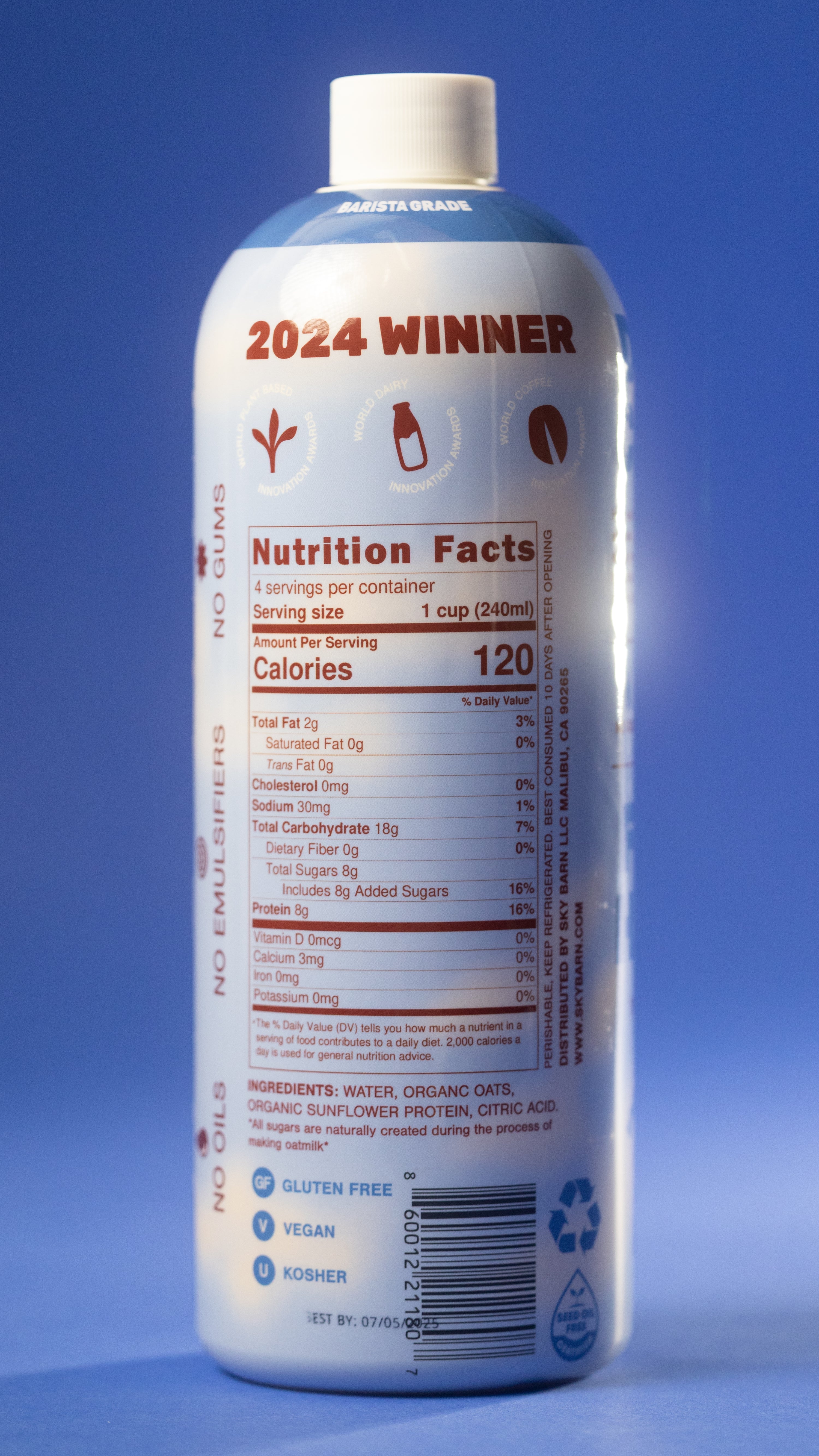 Barista grade bottle of original oat milk with sunflower protein on a cloudy sky background